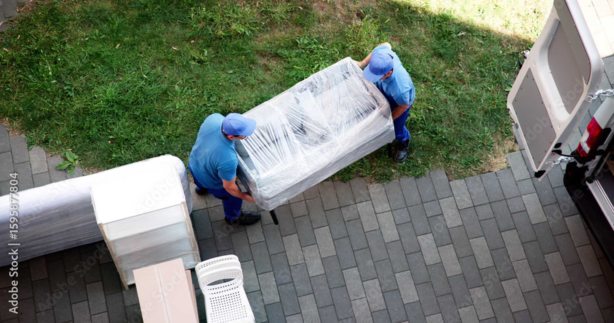 Flyttehjelp i Akershus med to flyttefolk som bærer plastinnpakket sofa til flyttebil for trygg transport.